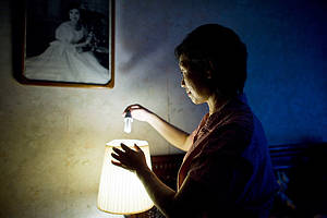 A Chinese women inserts a low-energy light bulb in her home in Shanghai. 